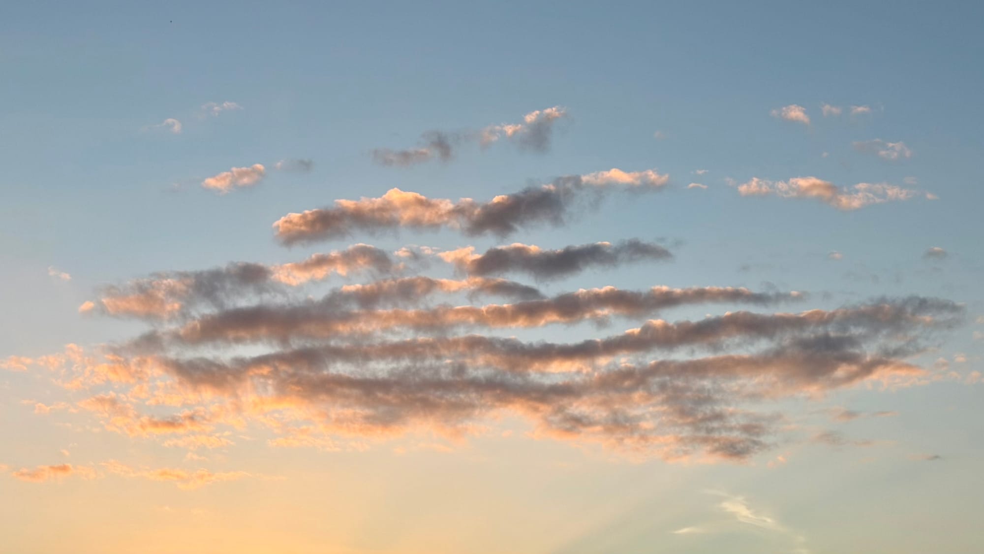 A view of some fluffy clouds above a sunset.